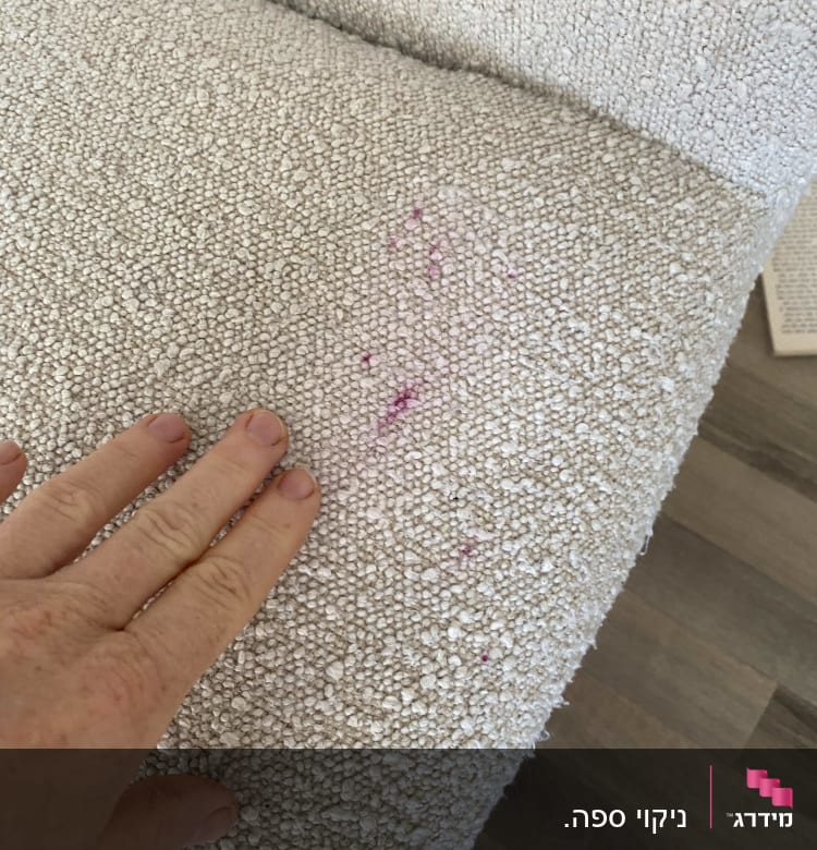 כתם ורוד על ספה בהירה עם יד נוגעת